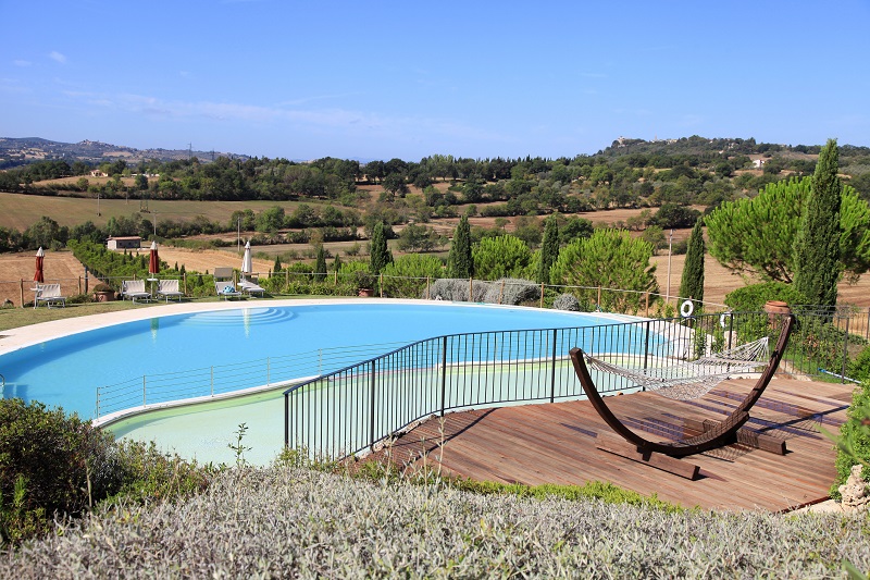 Una piscina di un albergo con vista sulle colline in Toscana